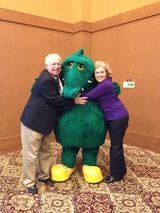 A man and woman posing with a large green dragon.